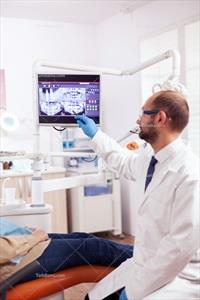 تصویر با کیفیت دندانپزشک در حال مشاهده عکس دندان بیمار